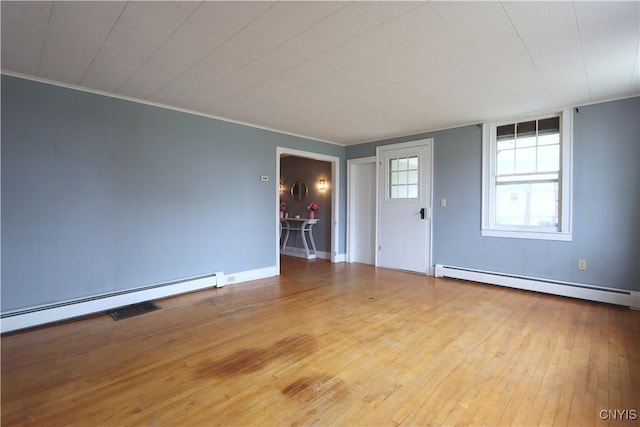 spare room featuring baseboards, ornamental molding, baseboard heating, and hardwood / wood-style floors