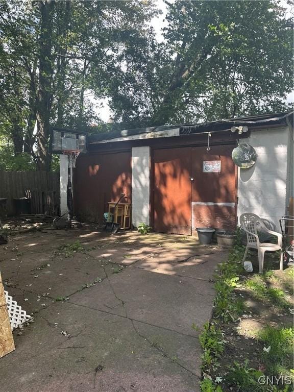 view of outbuilding with concrete driveway and fence