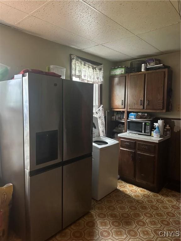 kitchen with dark brown cabinets, washer / clothes dryer, a drop ceiling, light countertops, and appliances with stainless steel finishes