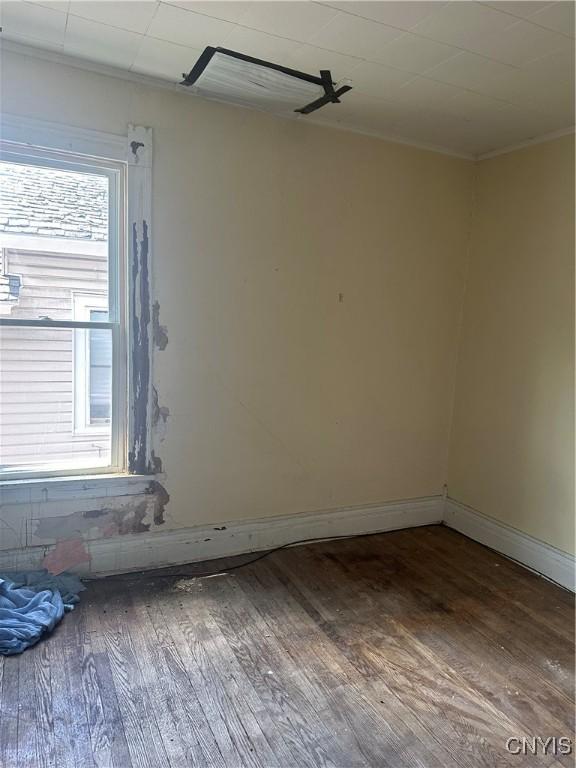 spare room featuring baseboards, ornamental molding, and wood finished floors
