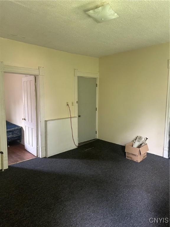 unfurnished room with carpet flooring and a textured ceiling