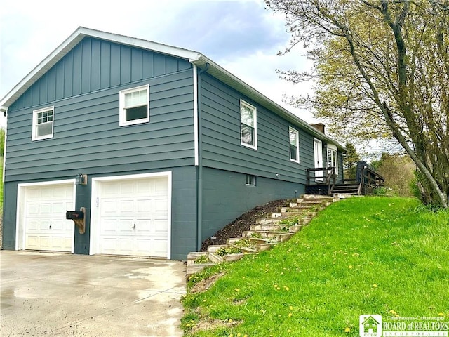 view of side of home featuring a garage, board and batten siding, a yard, and concrete driveway