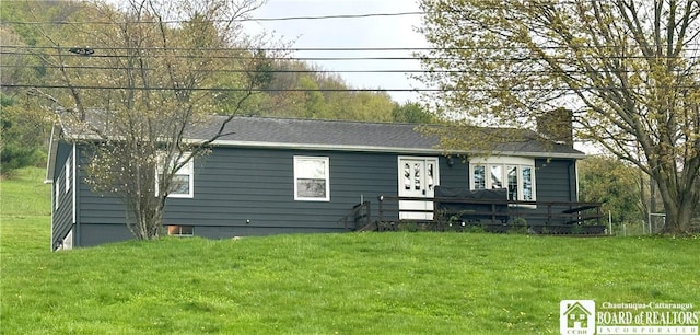 view of front of property featuring a wooden deck, a chimney, and a front yard