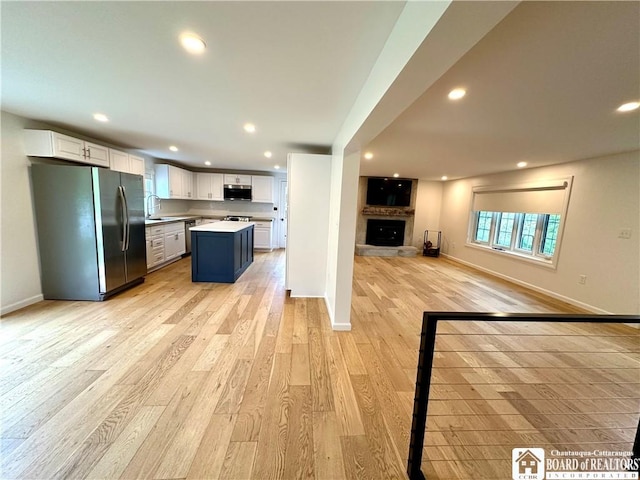 kitchen featuring a sink, light wood finished floors, stainless steel appliances, open floor plan, and recessed lighting