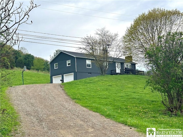 view of front of home featuring an attached garage, dirt driveway, a front lawn, and a chimney