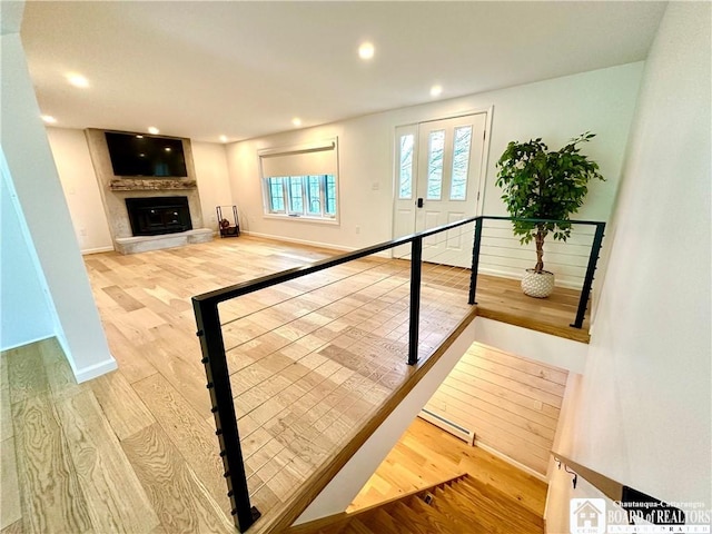 interior space featuring recessed lighting, wood finished floors, baseboard heating, and a large fireplace