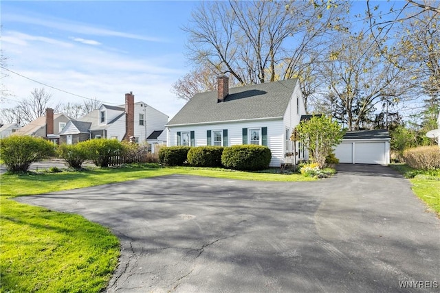 view of front facade with a garage, a chimney, aphalt driveway, and a front yard