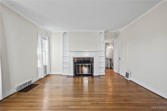 unfurnished living room featuring visible vents, a fireplace with flush hearth, crown molding, and wood finished floors