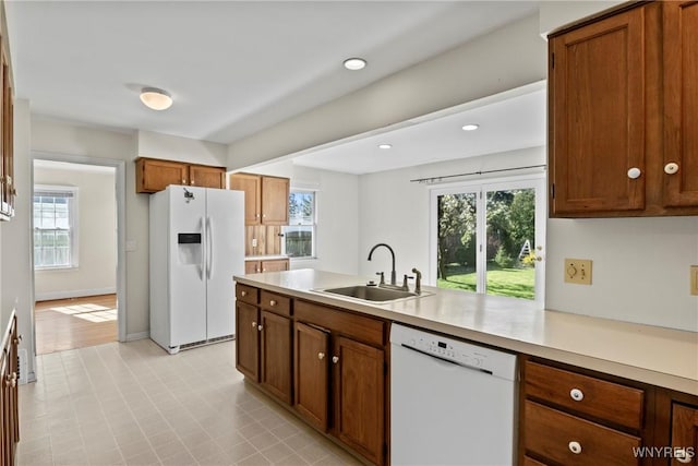kitchen with a sink, a healthy amount of sunlight, white appliances, and light countertops