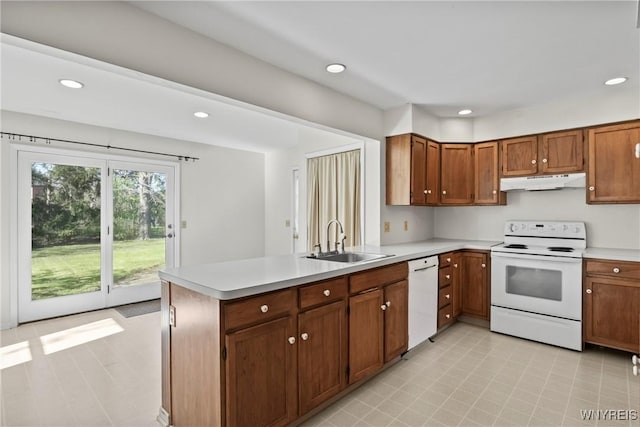 kitchen with a peninsula, white appliances, light countertops, under cabinet range hood, and a sink