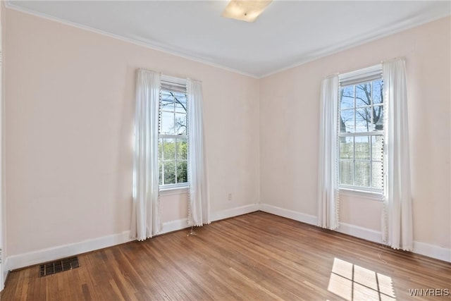 unfurnished room featuring baseboards, visible vents, plenty of natural light, and wood finished floors