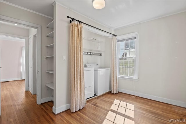 washroom featuring laundry area, crown molding, wood finished floors, baseboards, and washing machine and clothes dryer