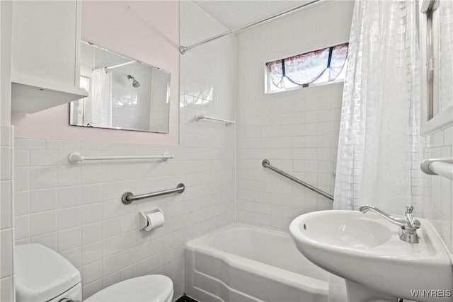bathroom featuring a sink, tile walls, shower / bathtub combination with curtain, and toilet
