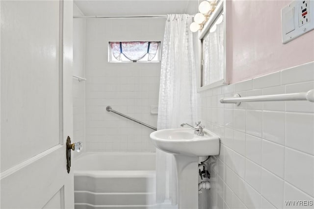 full bathroom with a sink, tile walls, and shower / bathtub combination with curtain