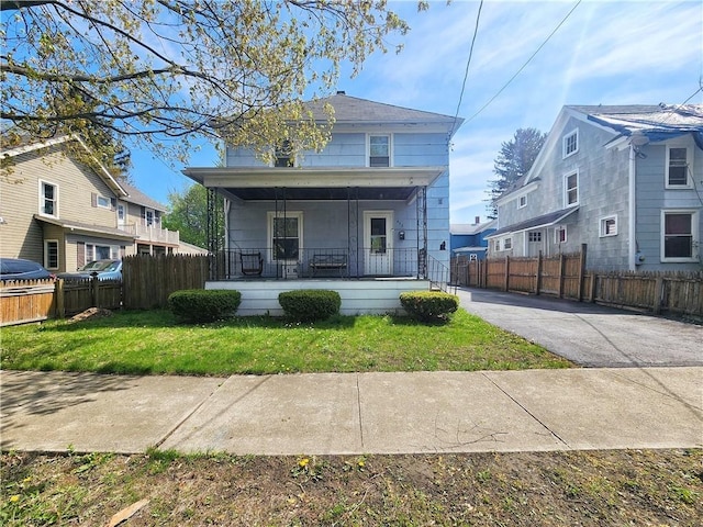 view of front of home with a porch, fence, and a front yard