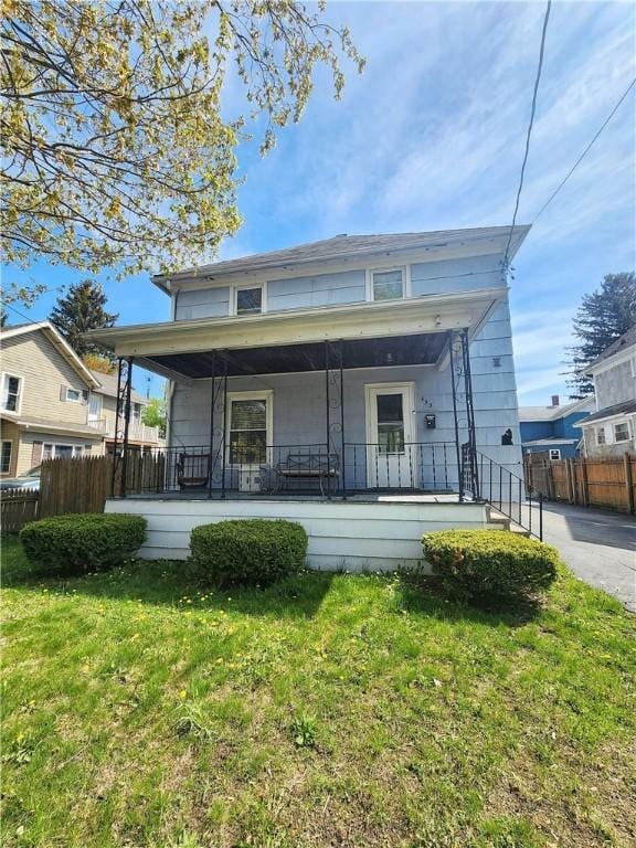 view of front of property with fence, a porch, and a front lawn