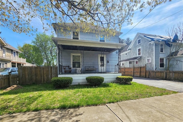 view of front facade with a front lawn, fence, and covered porch