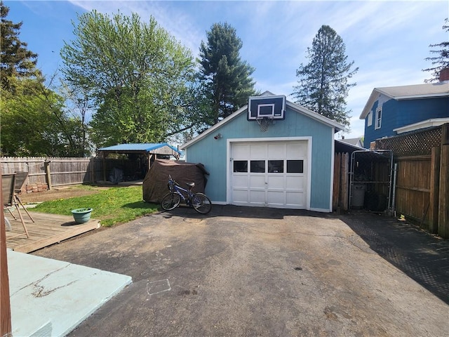 detached garage featuring fence and driveway