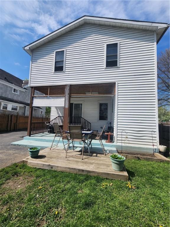 back of house with fence, a wooden deck, and a lawn