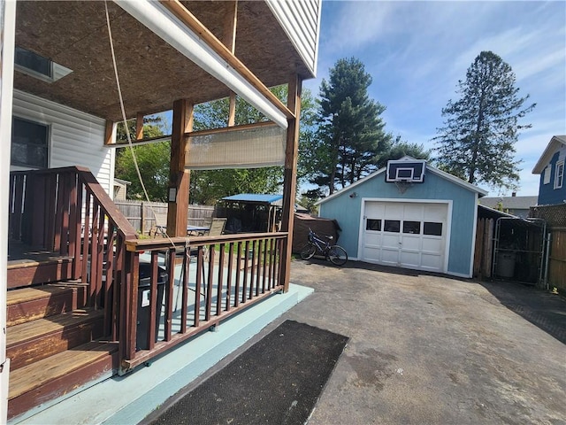 exterior space with a garage, fence, an outdoor structure, and aphalt driveway
