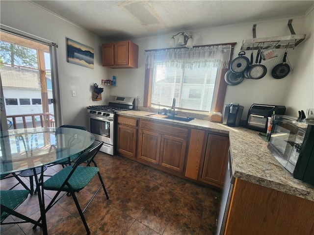 kitchen featuring stainless steel gas range, brown cabinets, black microwave, a sink, and ornamental molding