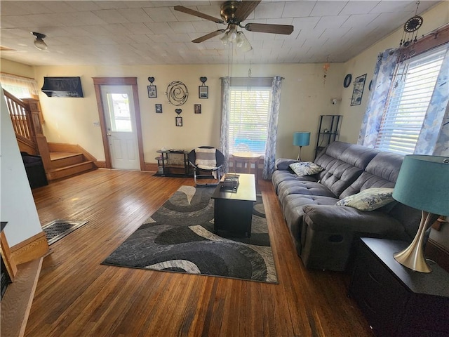 living room with plenty of natural light, a ceiling fan, stairs, and wood finished floors