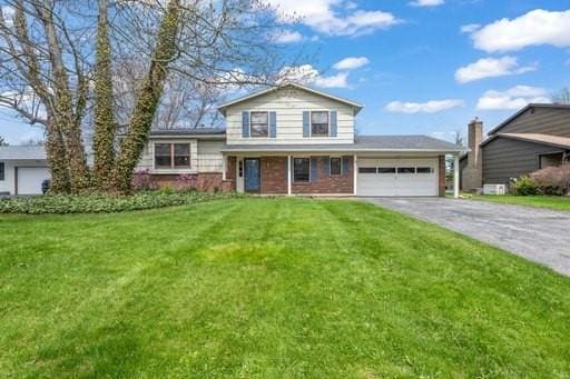 view of front of home featuring a garage, driveway, brick siding, and a front yard