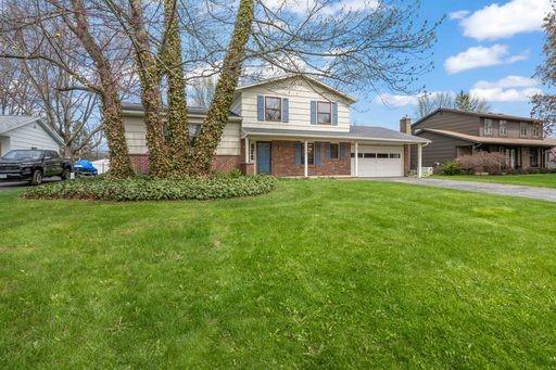 traditional-style house with a garage, driveway, and a front lawn