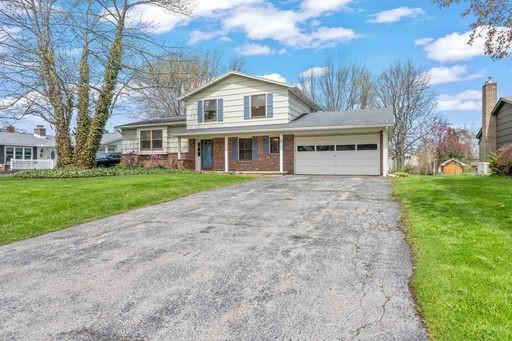 split level home with an attached garage, driveway, a front lawn, and brick siding