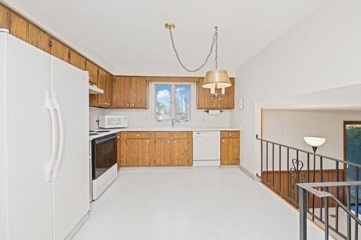 kitchen with brown cabinetry, light countertops, under cabinet range hood, and white appliances