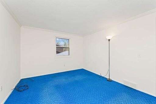 carpeted spare room with crown molding and visible vents