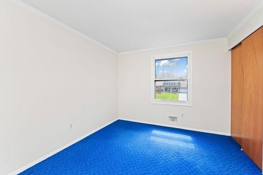 carpeted empty room featuring crown molding and baseboards