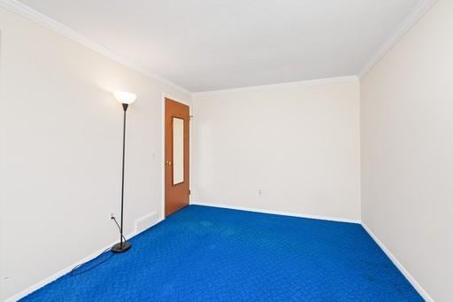 empty room featuring crown molding, carpet floors, and baseboards