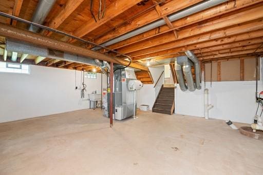 basement with heating unit, a sink, and stairway