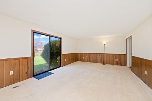 empty room featuring wooden walls, wainscoting, and carpet floors