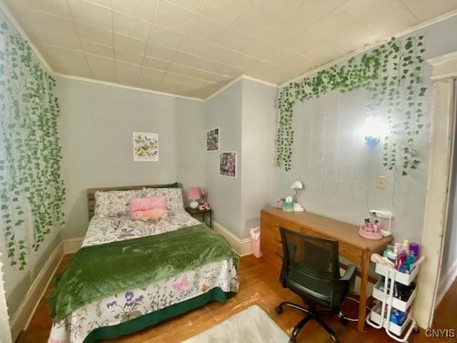 bedroom featuring baseboards, ornamental molding, and wood finished floors