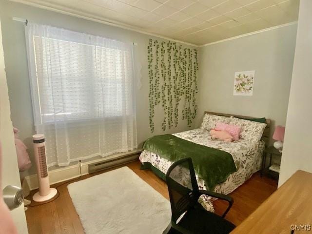 bedroom with ornamental molding and wood finished floors