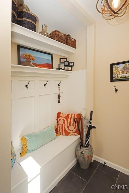 mudroom featuring dark tile patterned flooring, baseboards, and a notable chandelier