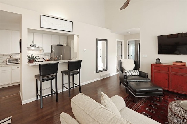 living area featuring dark wood-style flooring, ceiling fan, visible vents, and a toaster