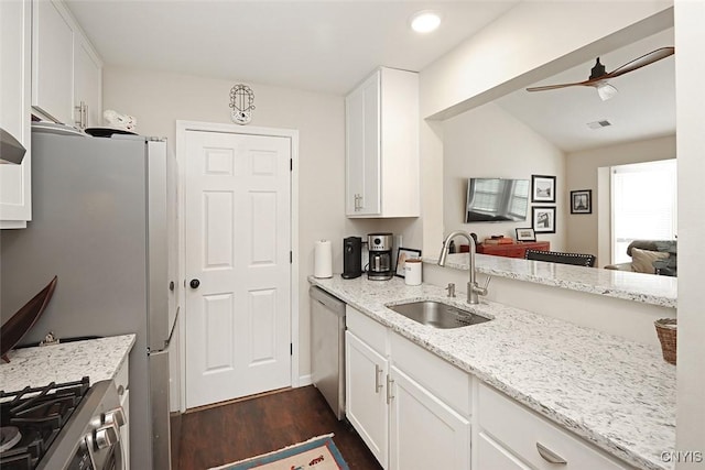 kitchen featuring light stone countertops, dark wood-type flooring, white cabinetry, a sink, and appliances with stainless steel finishes
