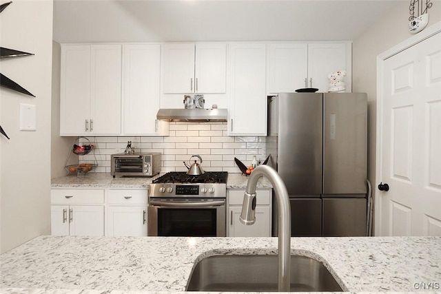 kitchen with backsplash, a sink, a toaster, under cabinet range hood, and stainless steel appliances