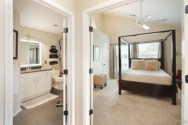 bedroom with visible vents, a sink, lofted ceiling, and ensuite bath
