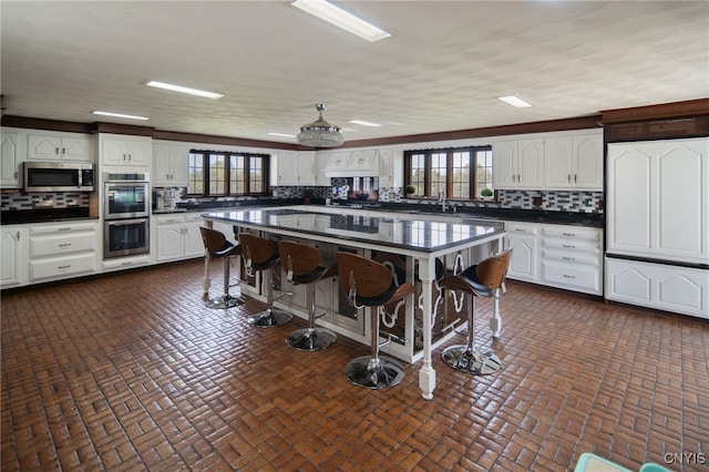 kitchen featuring dark countertops, tasteful backsplash, a breakfast bar, and stainless steel appliances
