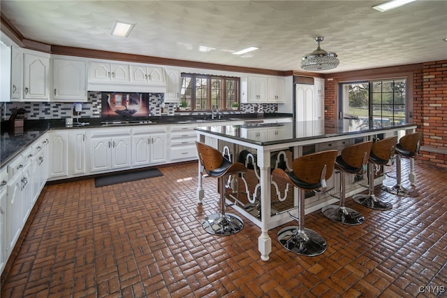 kitchen with dark countertops, brick floor, and white cabinets