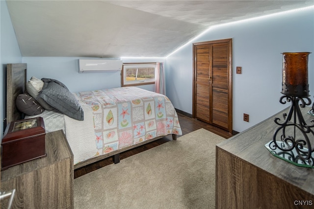 bedroom with wood finished floors, a closet, a wall mounted air conditioner, and lofted ceiling