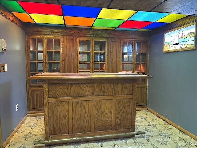 bar featuring baseboards, light floors, and a bar