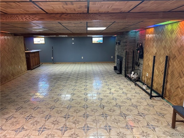 basement with a healthy amount of sunlight, light floors, and wood walls