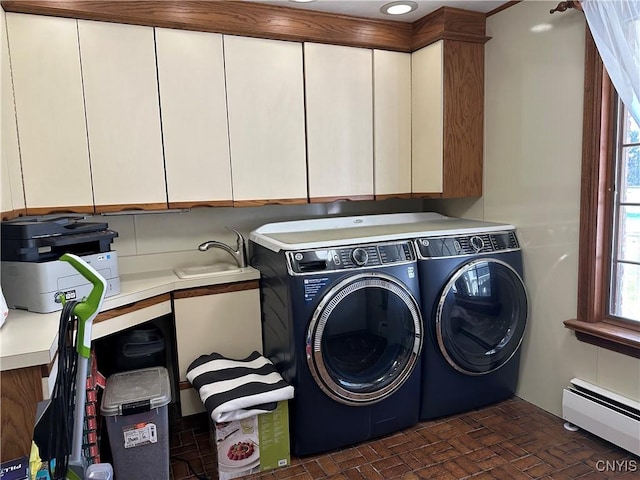 laundry area featuring baseboard heating, cabinet space, a sink, brick patterned floor, and washer and clothes dryer