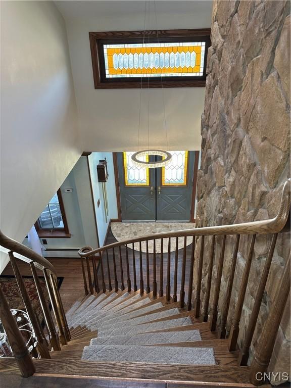 staircase with wood finished floors and a towering ceiling