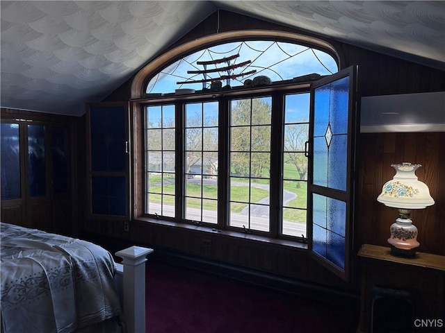 bedroom with wooden walls, multiple windows, carpet flooring, and lofted ceiling